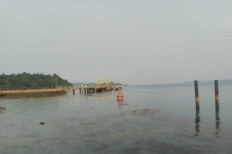 Panorama Pelabuhan Roro Jagoh, Singkep Barat, Kabupaten Lingga, saat matahari mulai naik di ufuk timur. Dermaga kayu dan beton membentang ke arah laut, tempat kapal-kapal roro ASDP bersandar setiap minggu. Dari pelabuhan kecil inilah, hasil bumi Pulau Singkep—sagu, jengkol, petai, dan aneka sayuran—memulai perjalanannya menyeberangi selat menuju Tanjungpinang dan Batam. (Foto: Jali)
